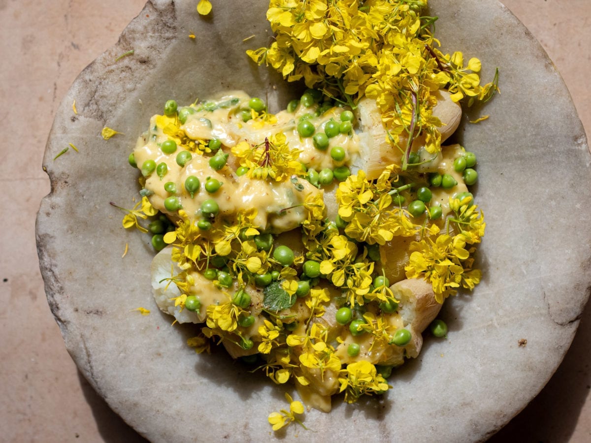 Za'atar potato salad on a ceramic plate finished with yellow flowers