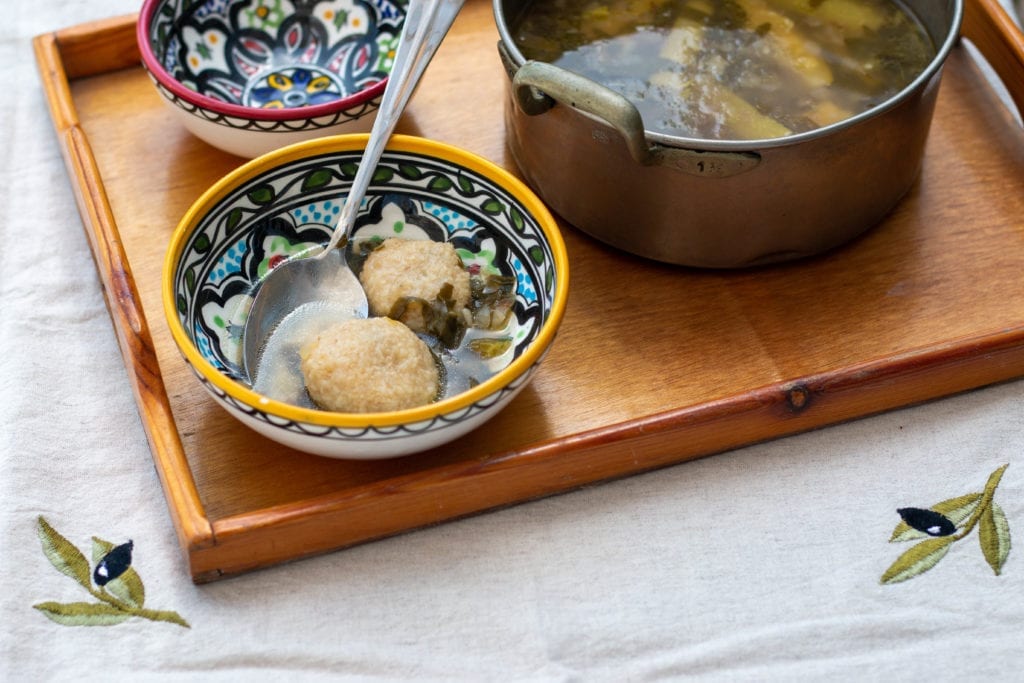 Iraqi dumpling soup called kubbeh in a pot with two ceramic bowls next to it