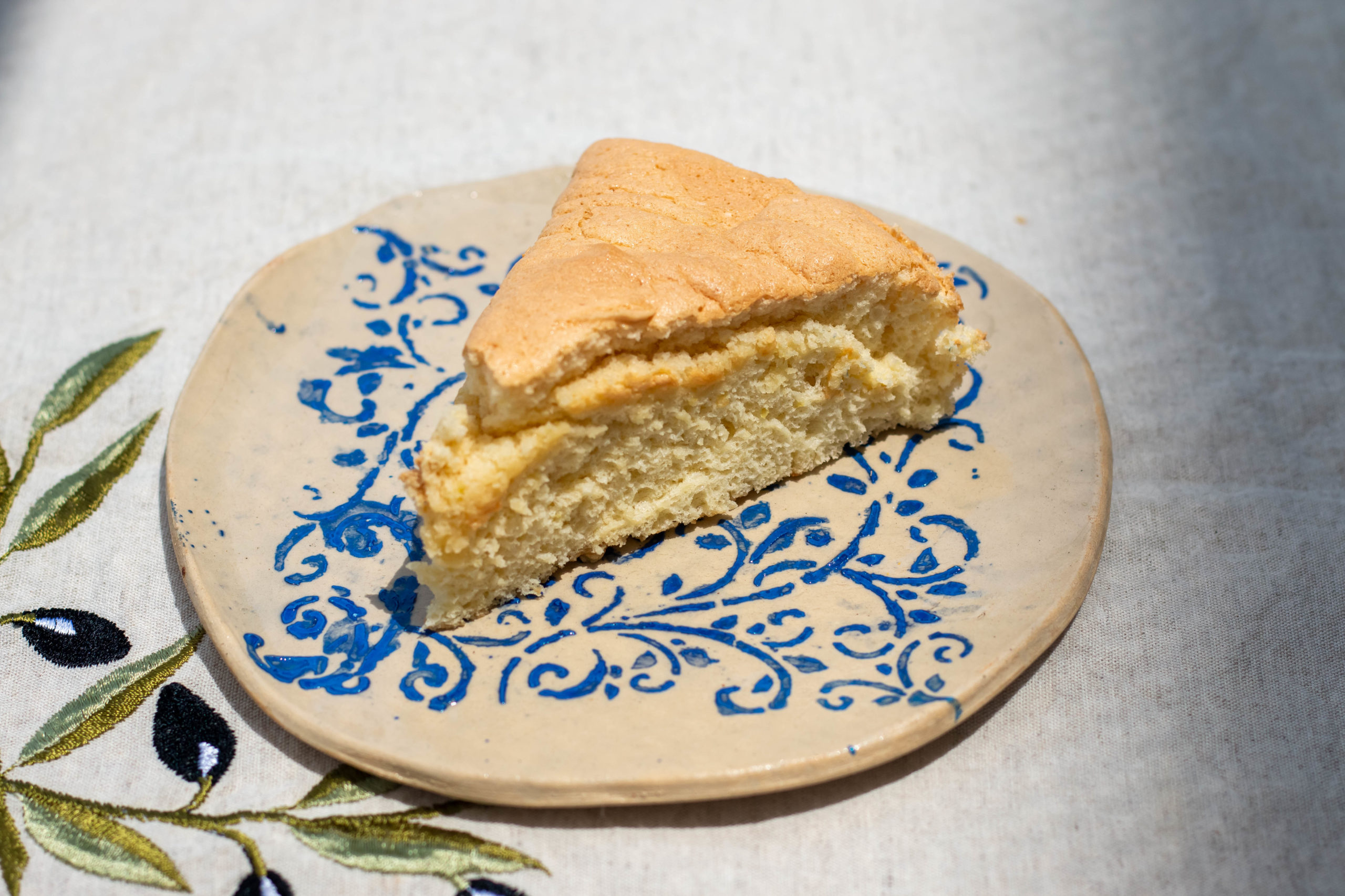 Slice of sponge cake on a cream colored plate with a blue pattern