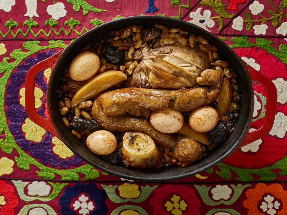 Hamin (cholent) in an oval Dutch oven with eggs, beans, and bone marrow
