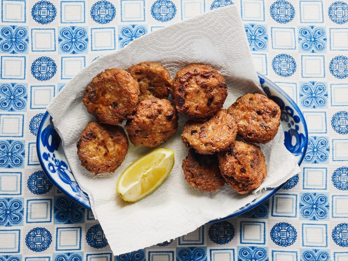 Bread and meat patties on a paper towel with lemon atop a blue and white mat