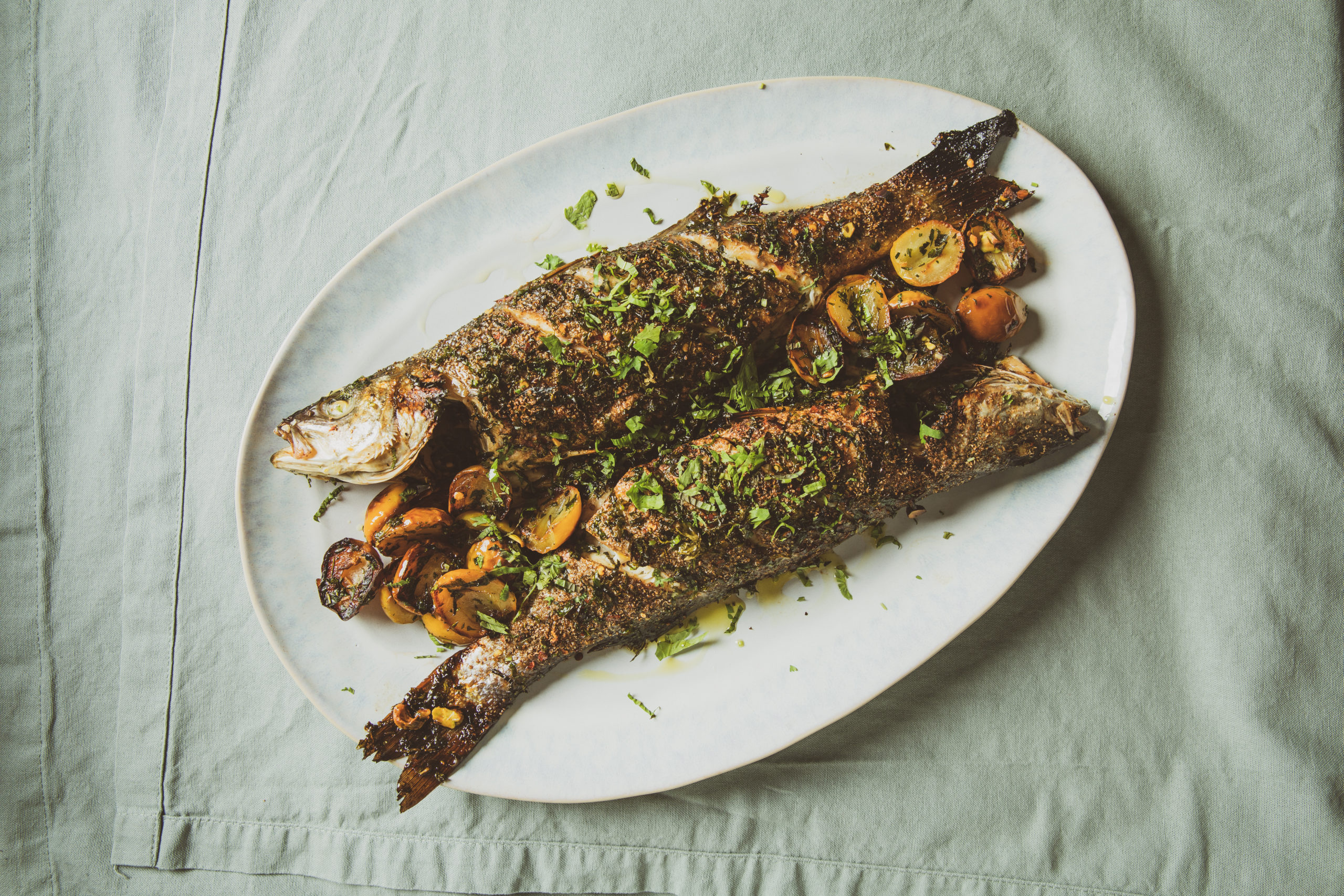 Roasted whole fish with pomegranate molasses on a white platter