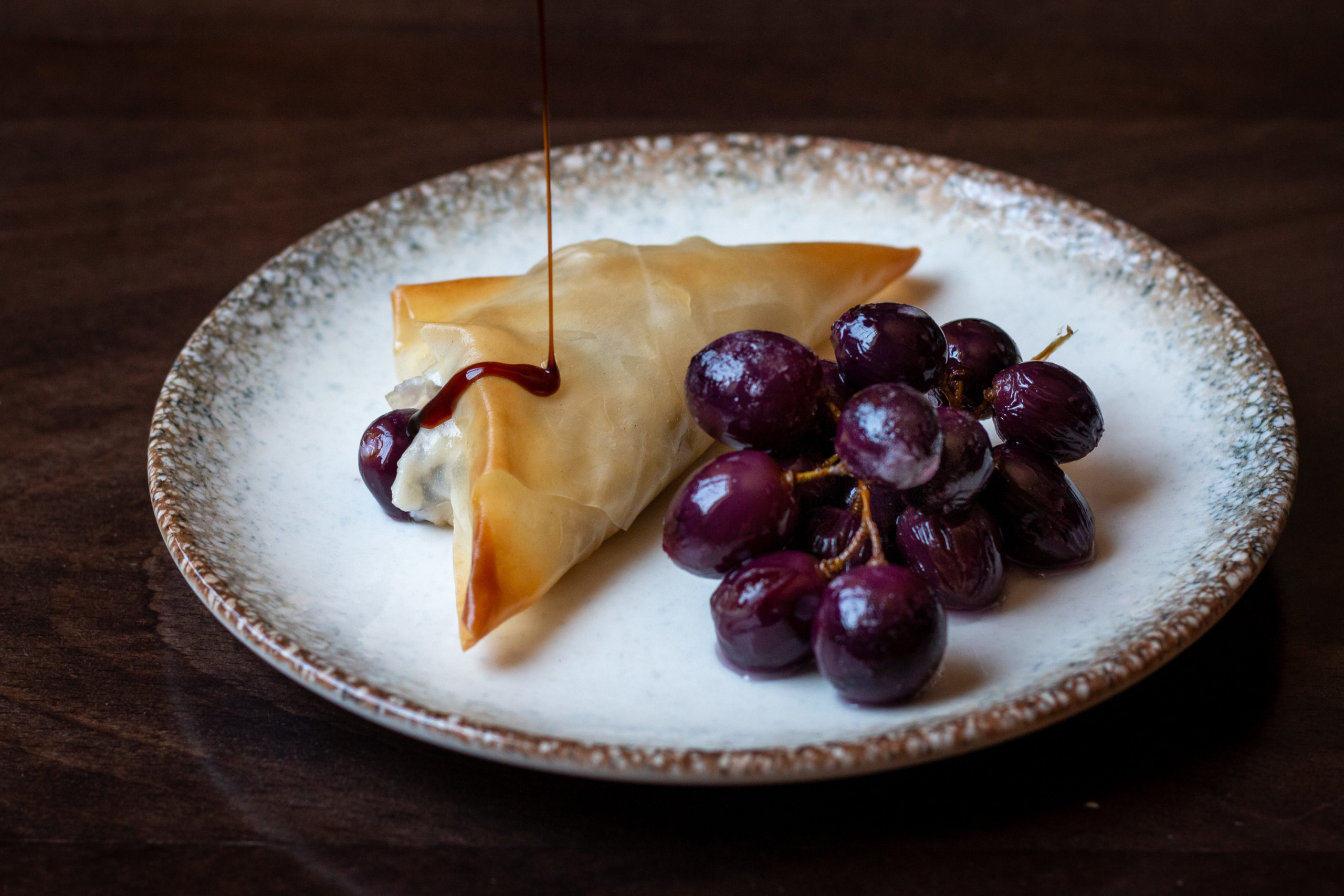 Filo triangles stuffed with kashta, grapes and raisins on a white plate