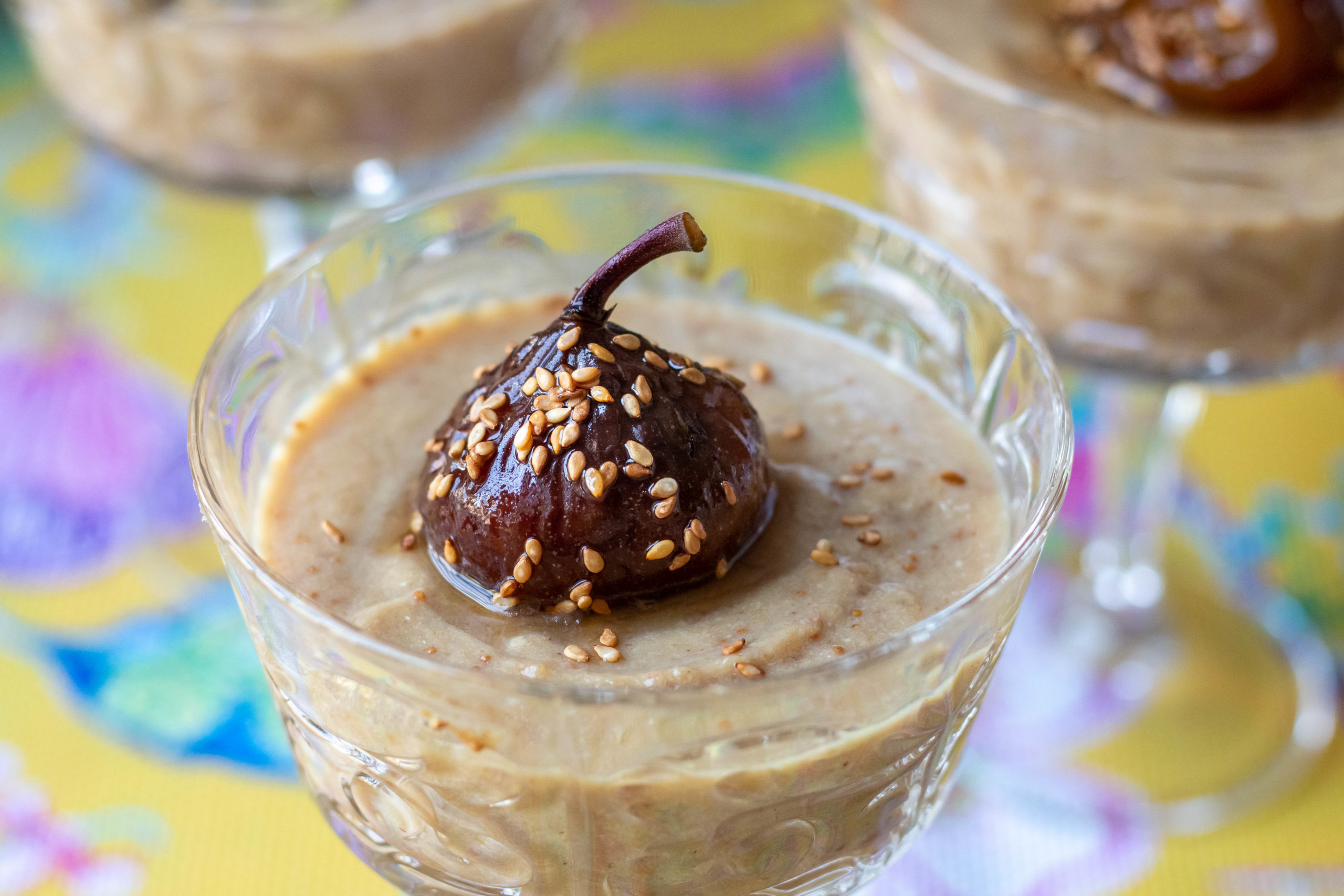 Dried fig malabi (milk pudding) in a glass on a colorful tablecloth