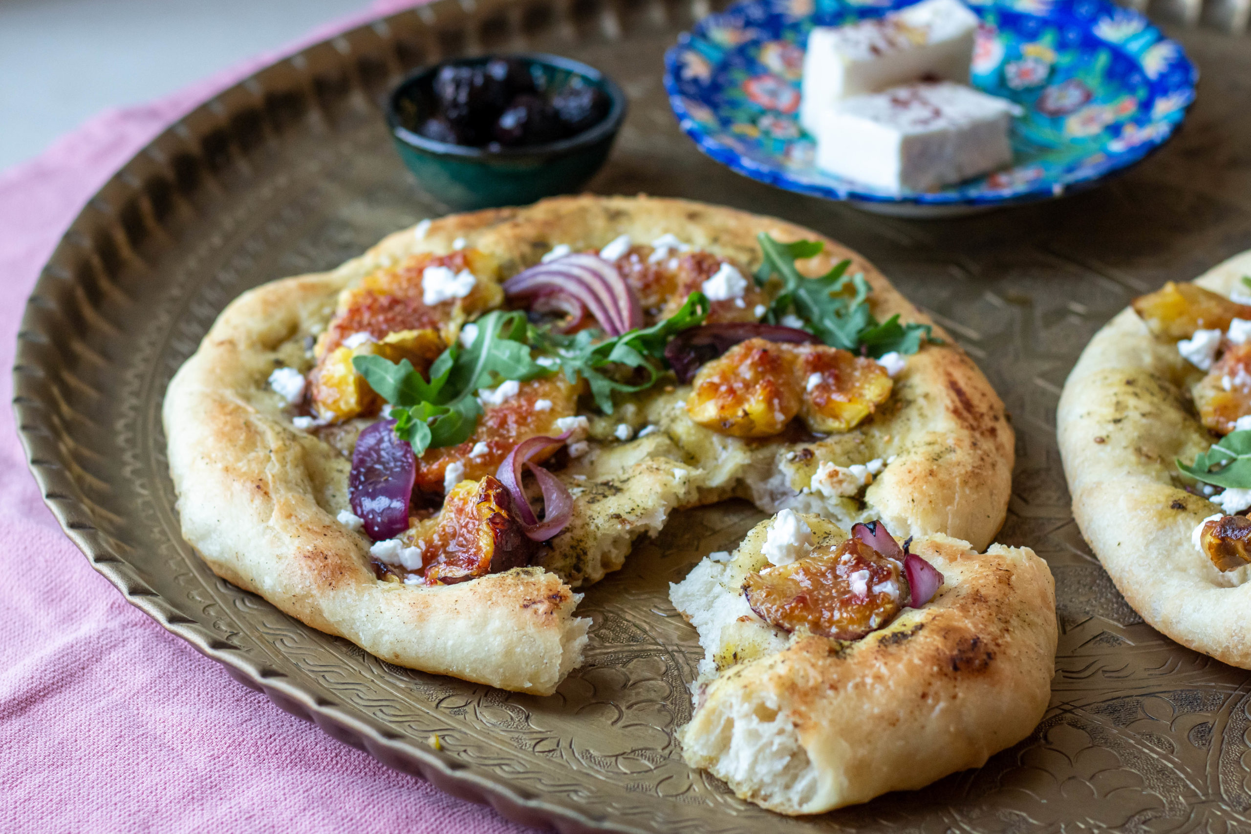 Manakish (flatbread) with figs and za'atar on a brass platter.