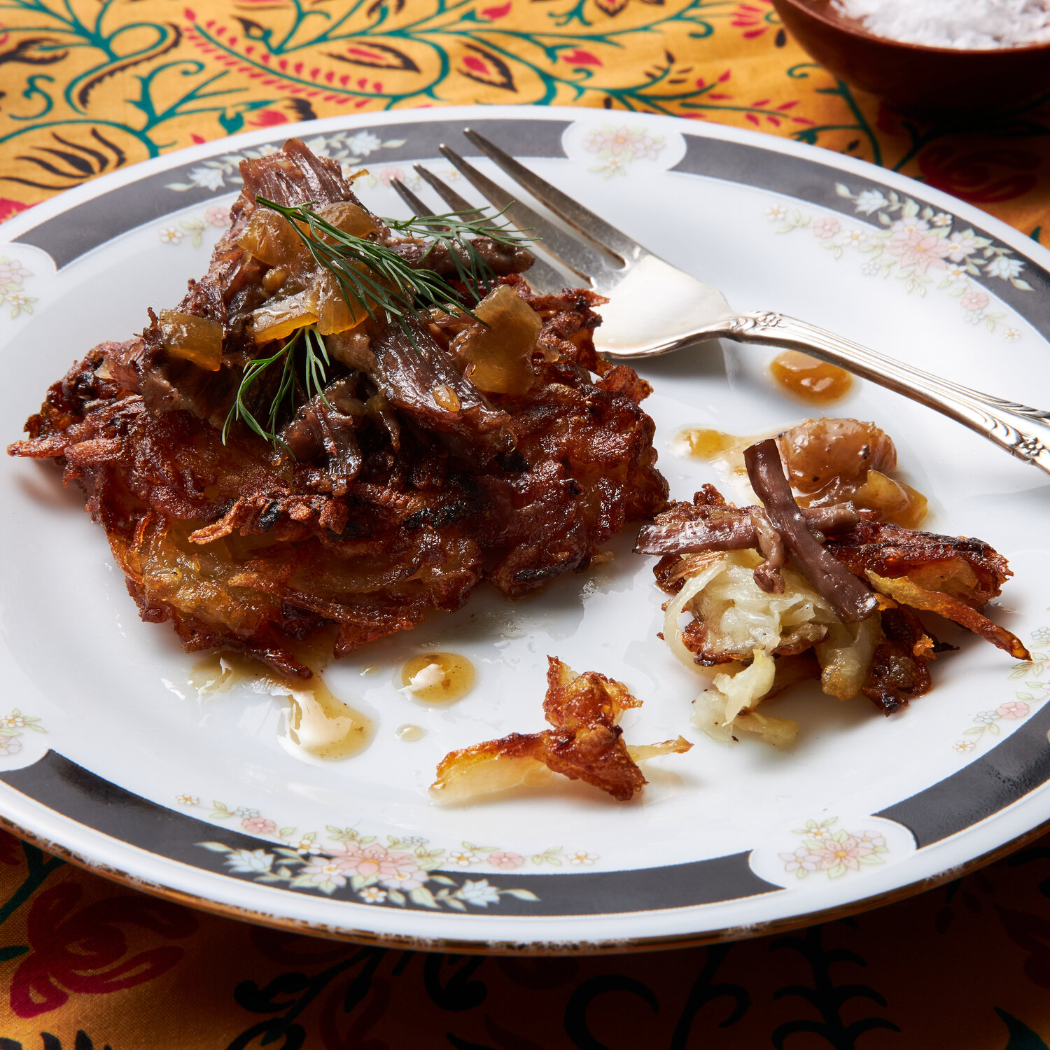 Latkes topped with braised beef and onions on a white plate