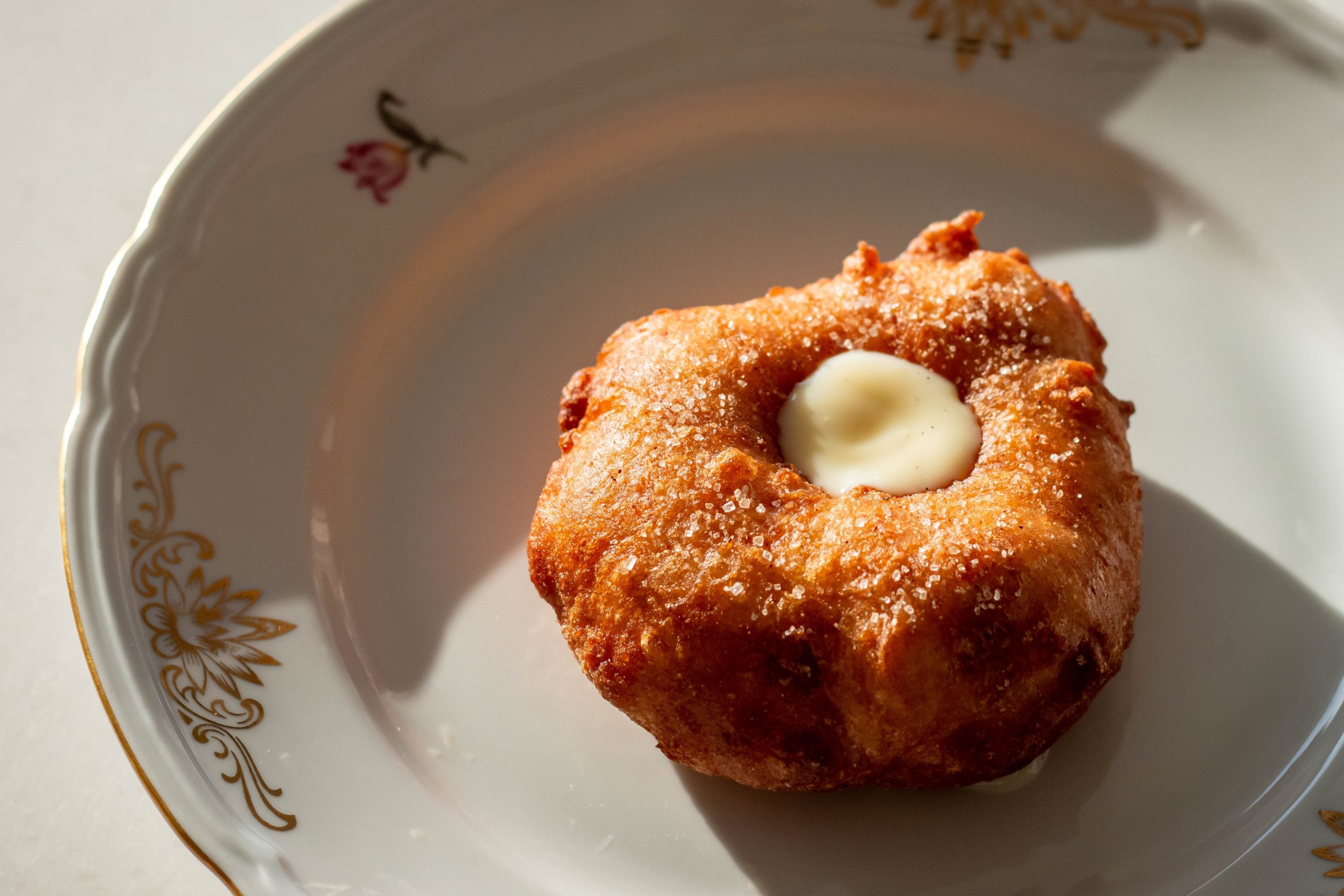 Sfinj doughnut with rosewater pastry cream on white plate