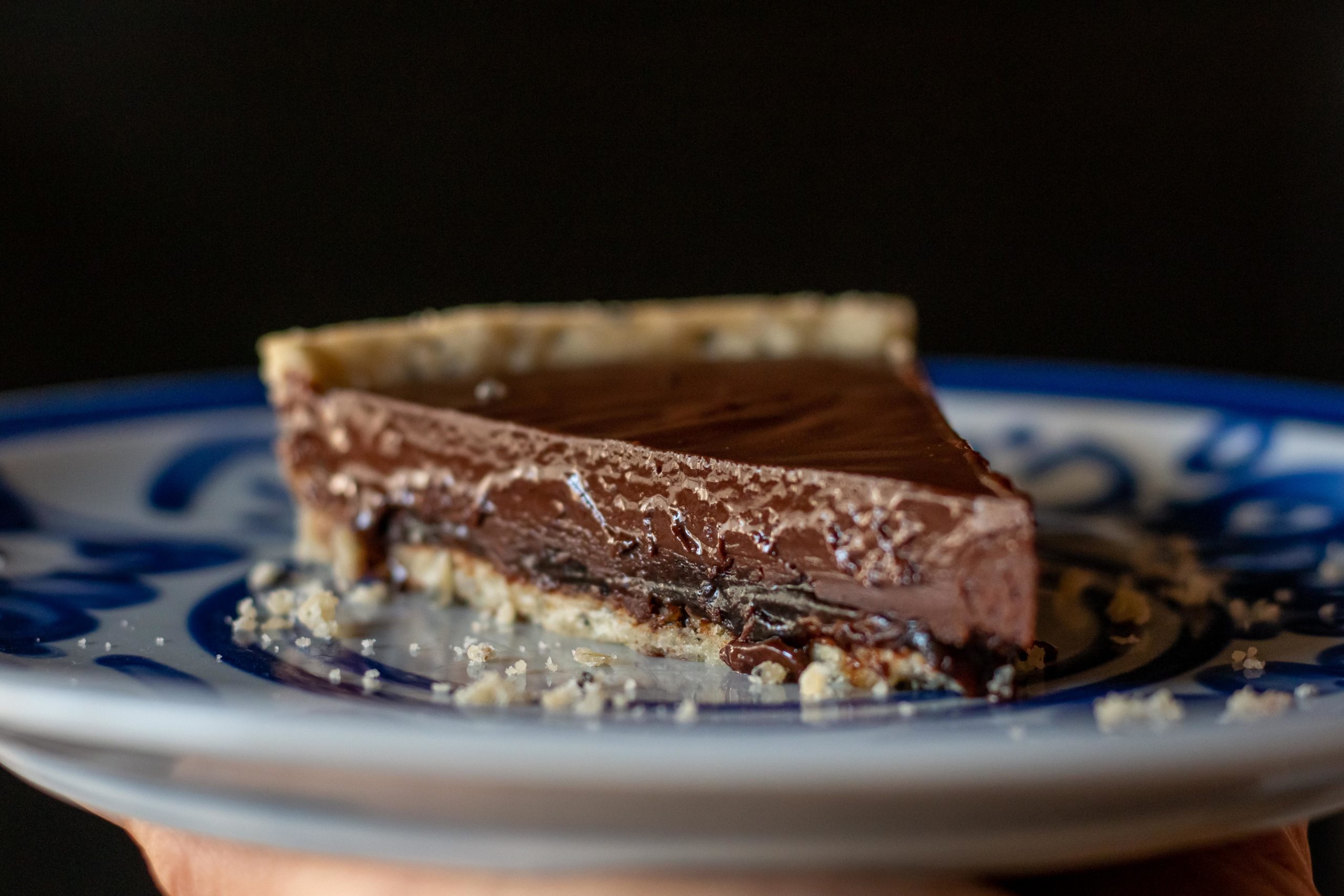 Slice of chocolate and olive oil tart on a blue and white plate
