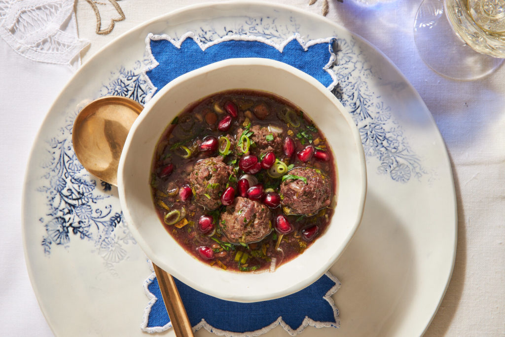 White bowl with meatballs, pomegranate seeds and scallions