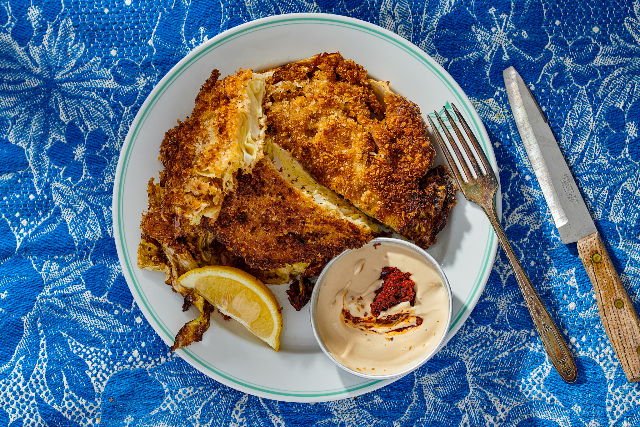 Cabbage schnitzel on white plate atop blue tablecloth