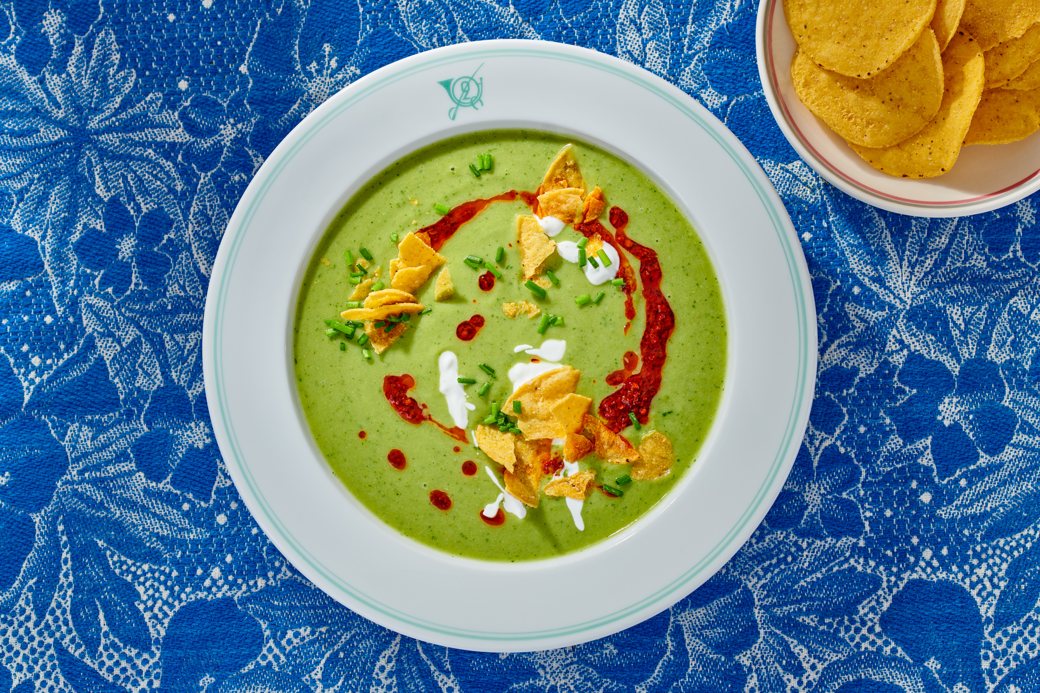 White bowl with green soup on blue tablecloth