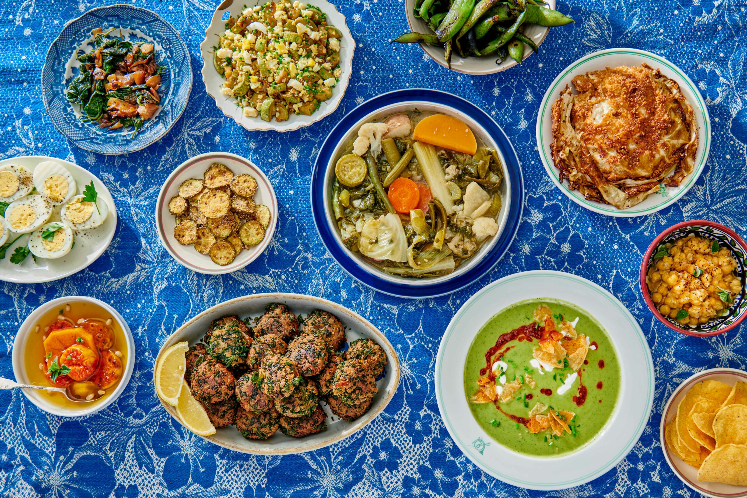 Vegetable recipes in various bowls on blue floral tablecloth