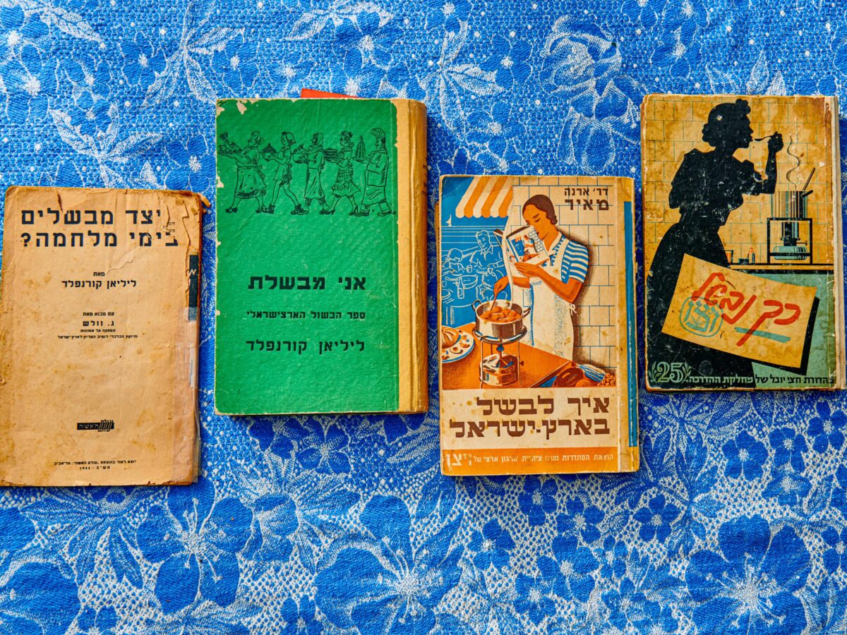 Vintage Hebrew cookbooks on blue floral tablecloth