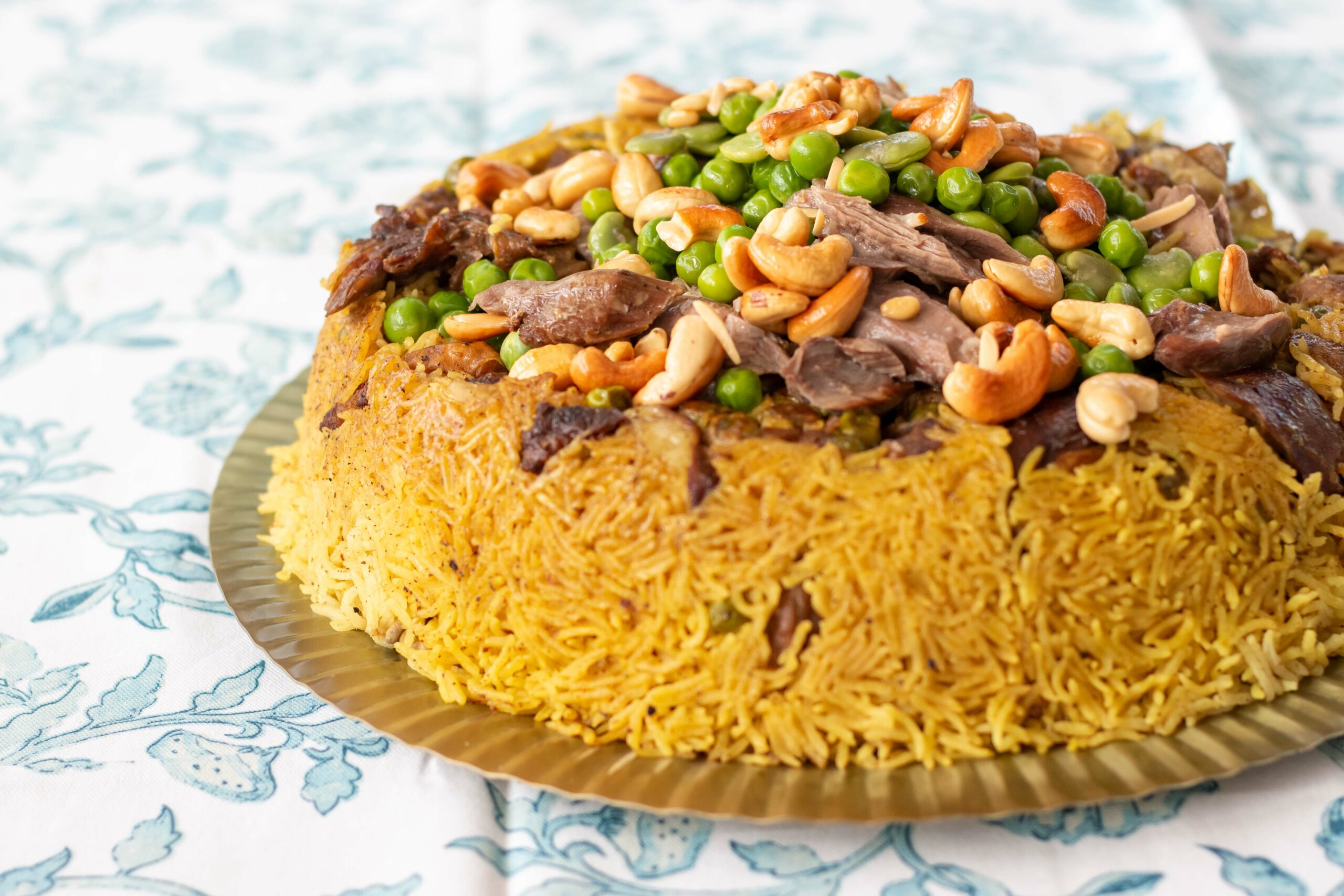 Rice casserole topped with fava beans, meat, and cashews