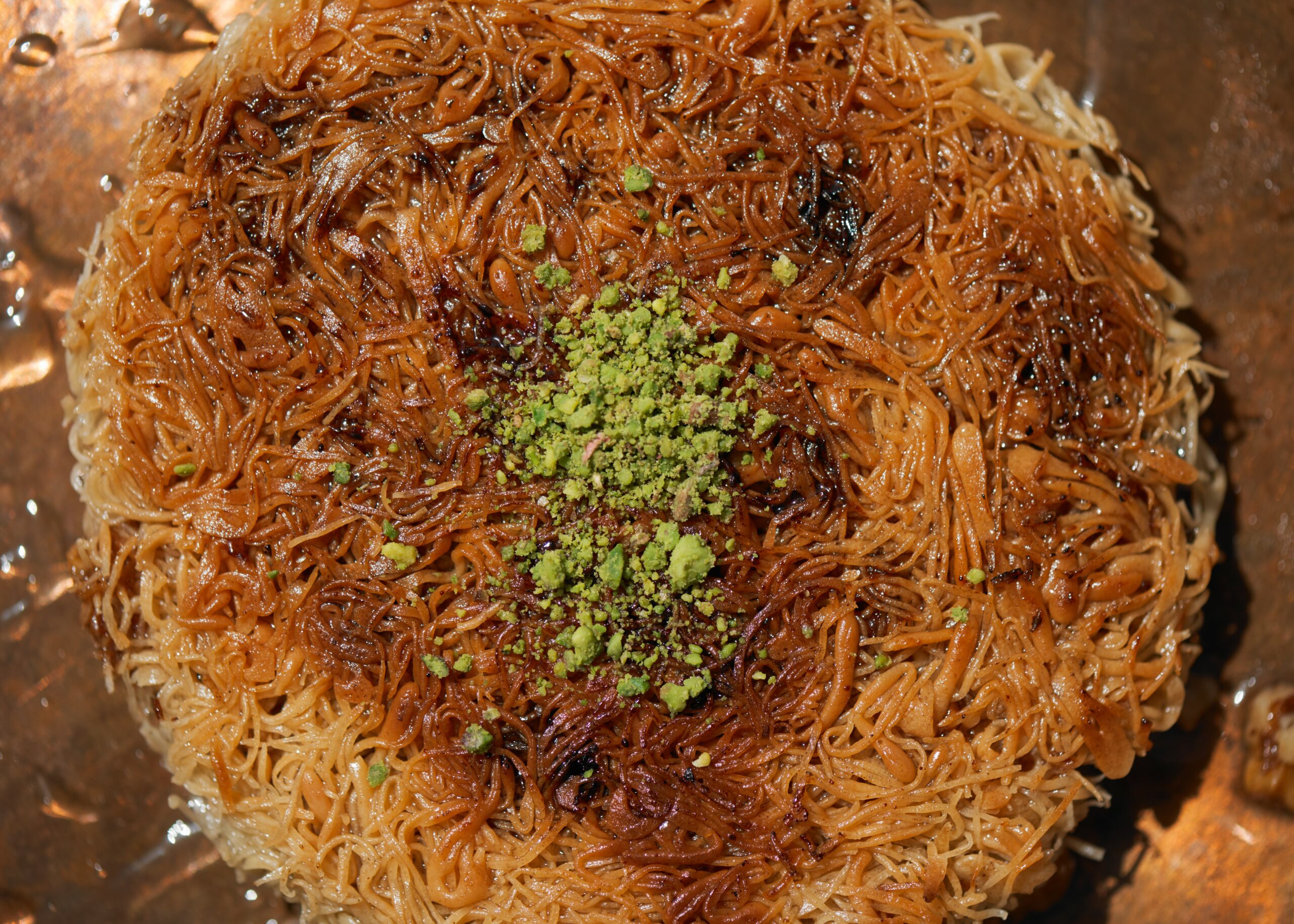 Traditional knafeh made with noodles of dough and topped with crushed pistachios