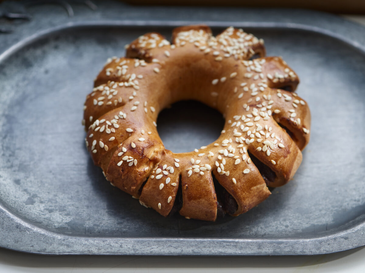 Ring-shaped pastry with sesame seeds on gray tray