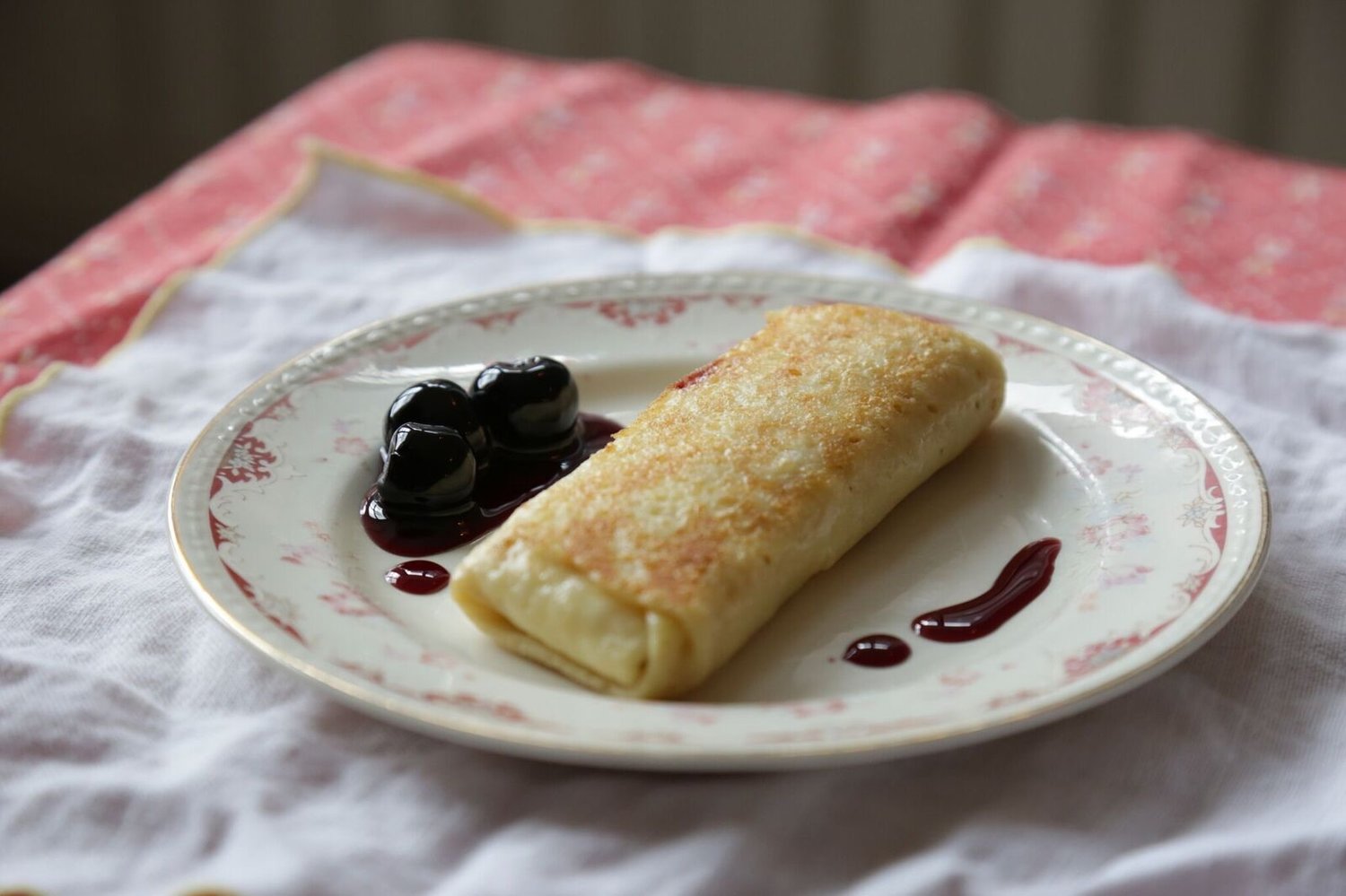 Blintz with cherries on a white plate