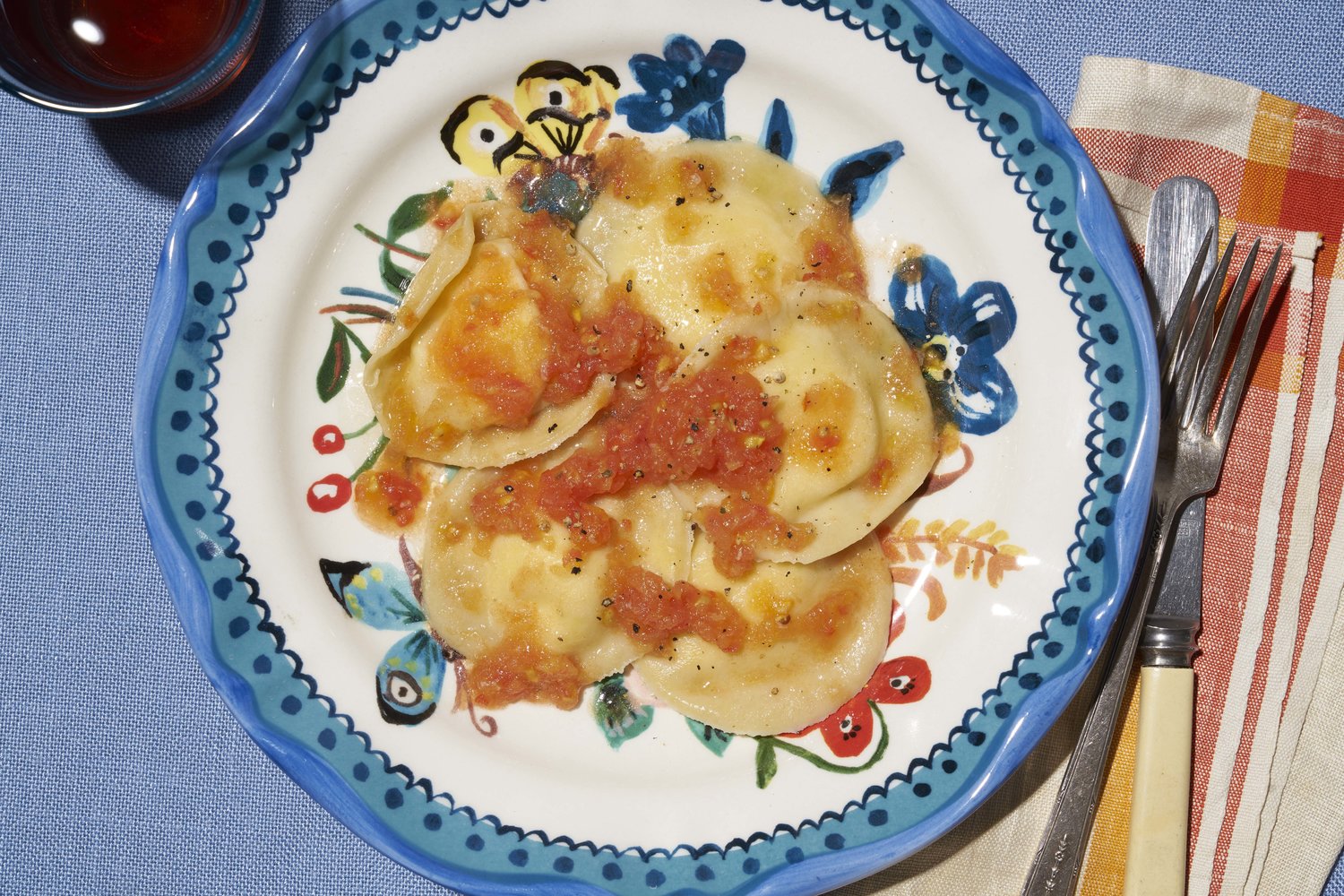 Ravioli or calzones with tomato sauce sit atop a white and blue ceramic plate