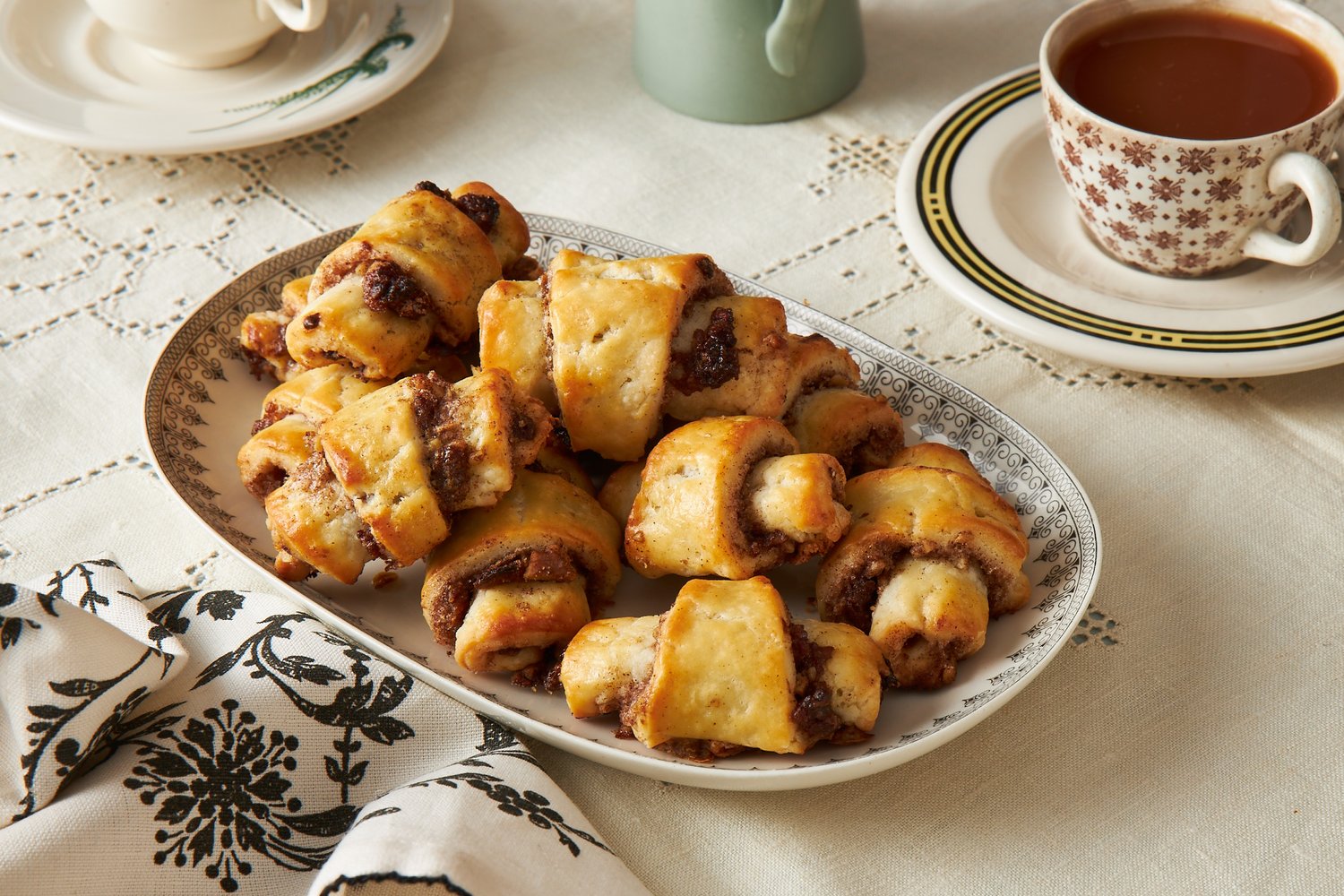 Rugelach pastries on oval tray atop cream tablecloth