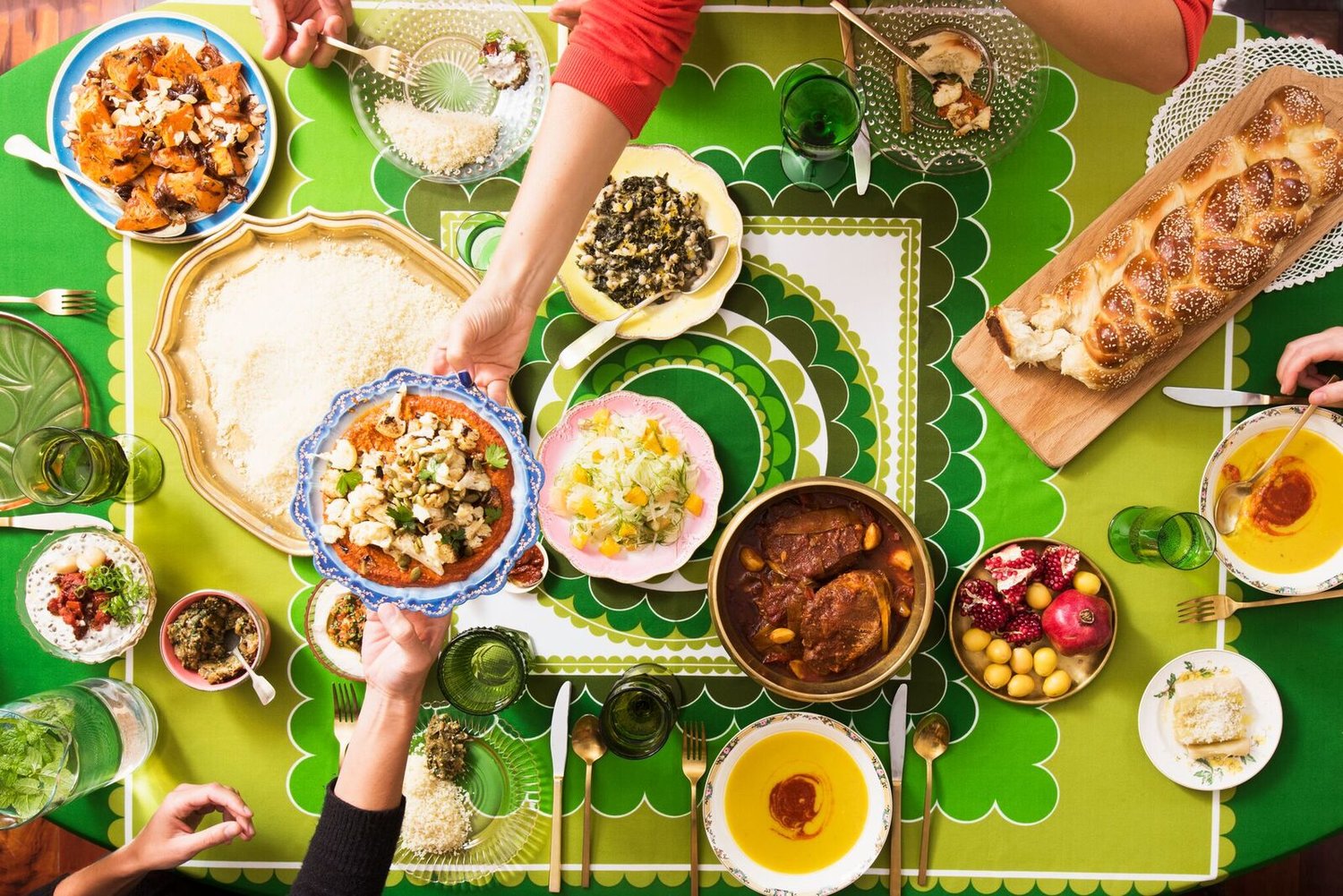 Sukkot spread including challah, fava bean soup, couscous and more on green tablecloth