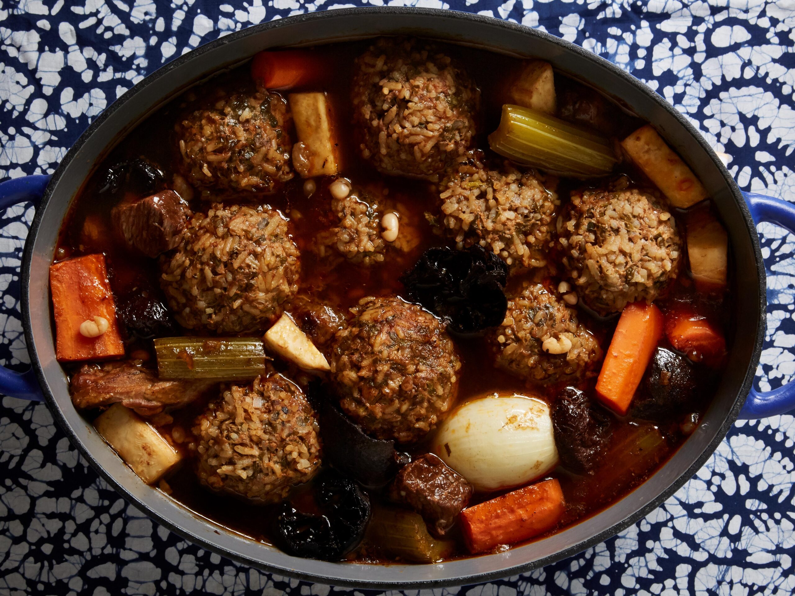 Persian meatballs made with rice in large dutch oven with chunks of carrots, onions, and prunes