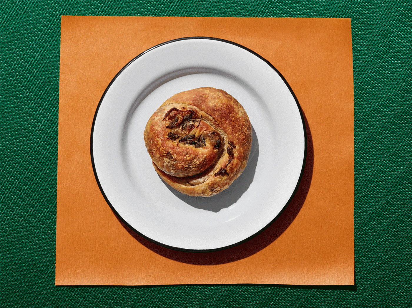 Boyos, a savory Sephardi pastry, on a white plate atop orange and green background