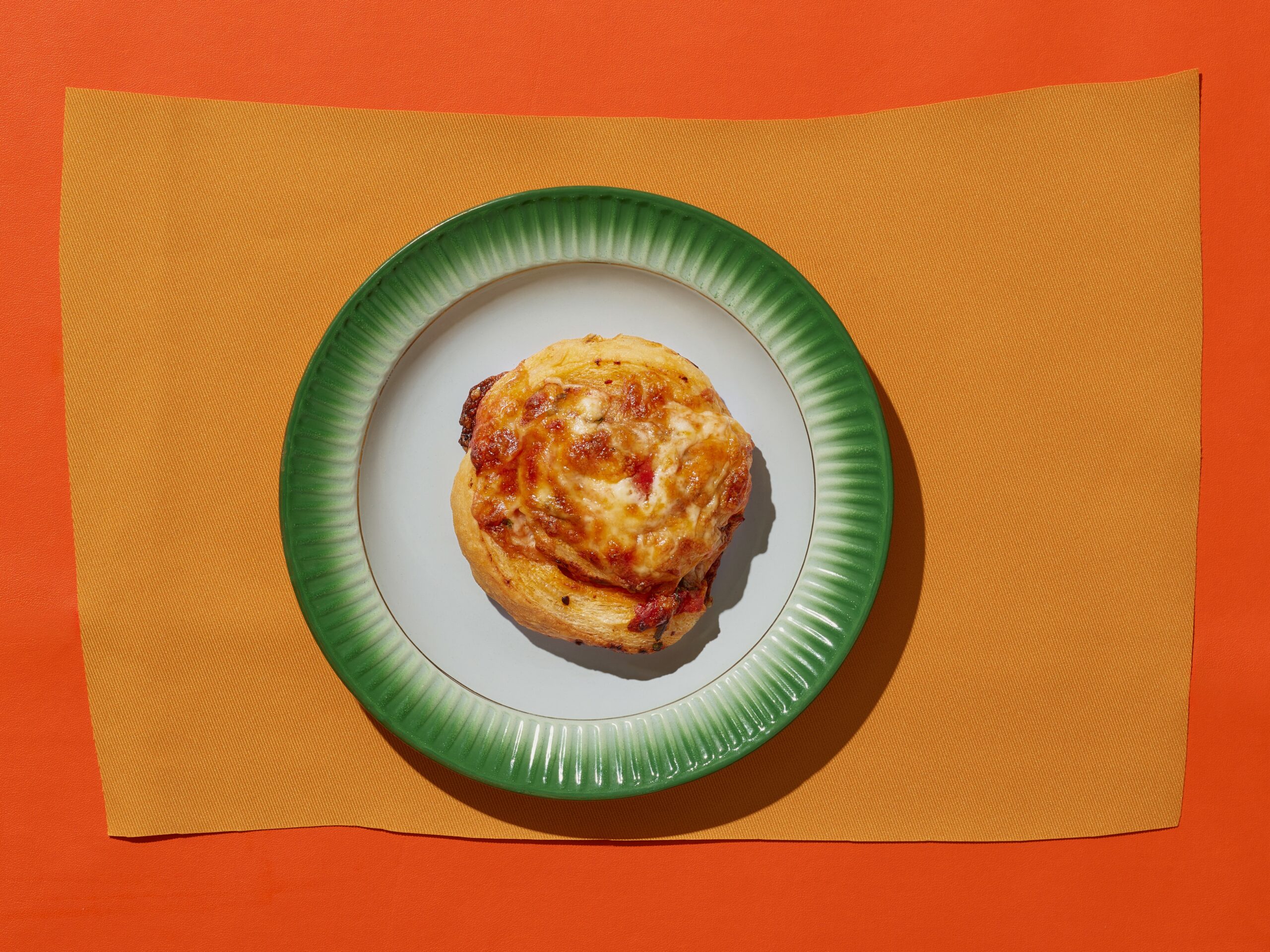 Pizza bourekas on a green and white plate atop orange background