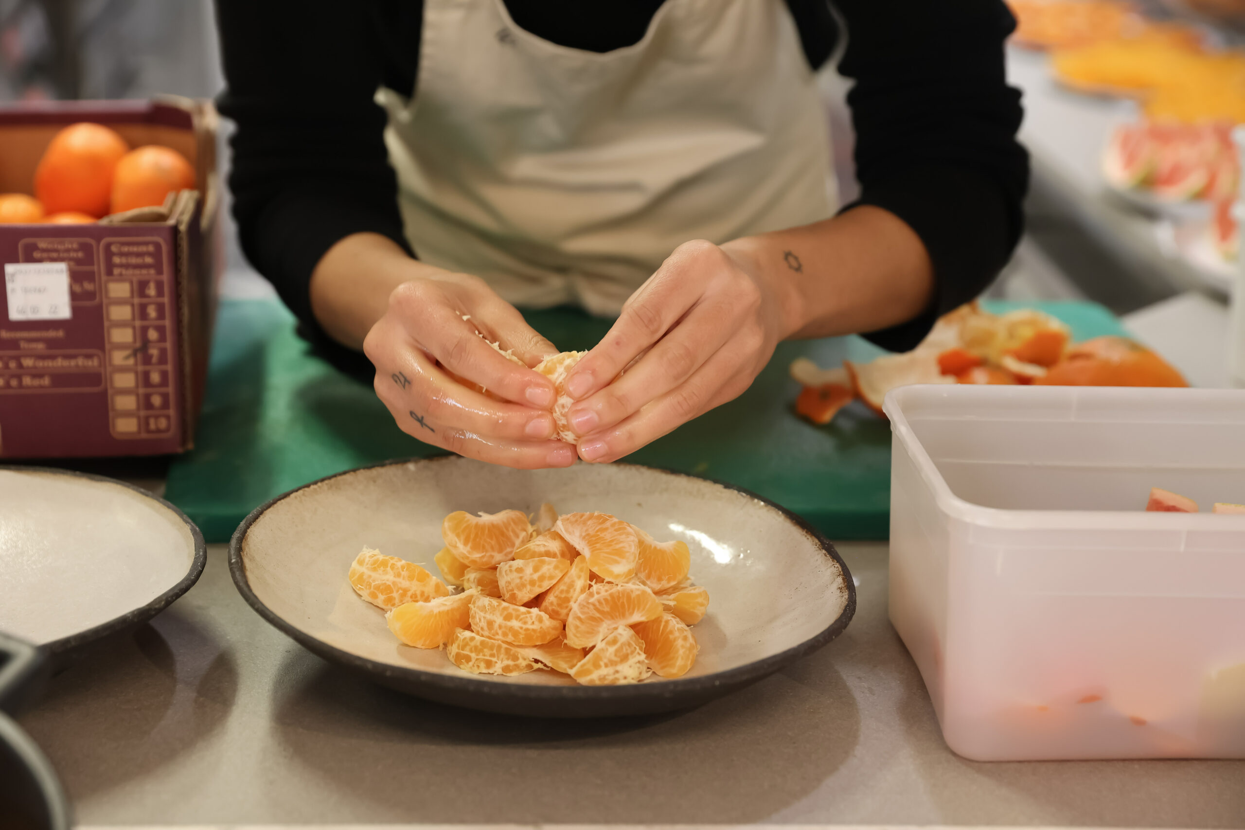 Hands pulling apart segments of citrus over large bowl