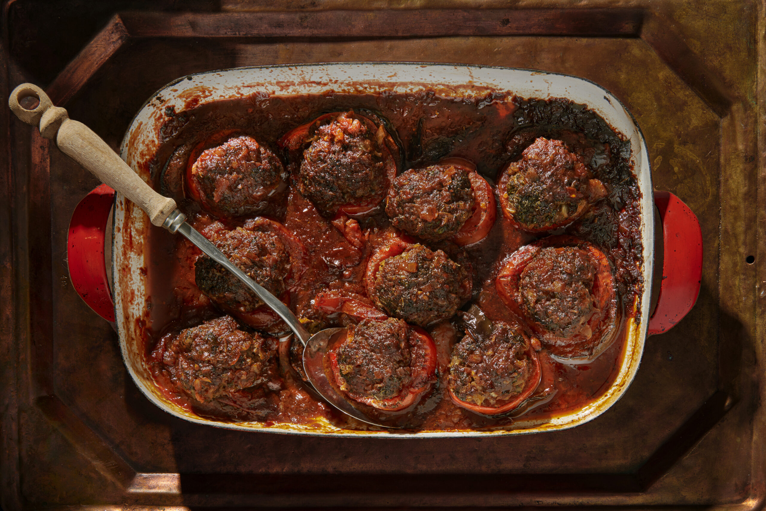 Beef stuffed vegetables in red baking dish with serving spoon