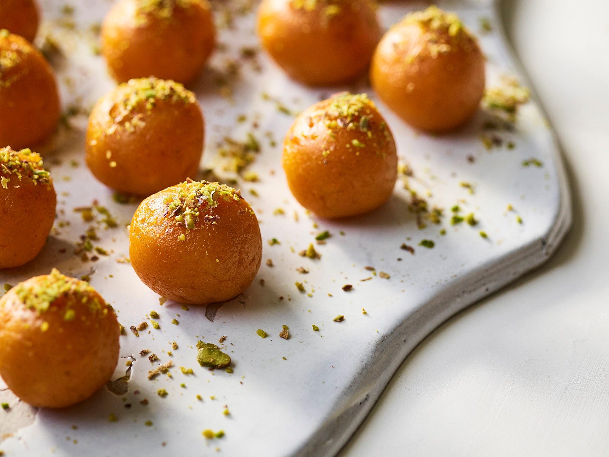 Persian carrot and pistachio candy on white ceramic tray