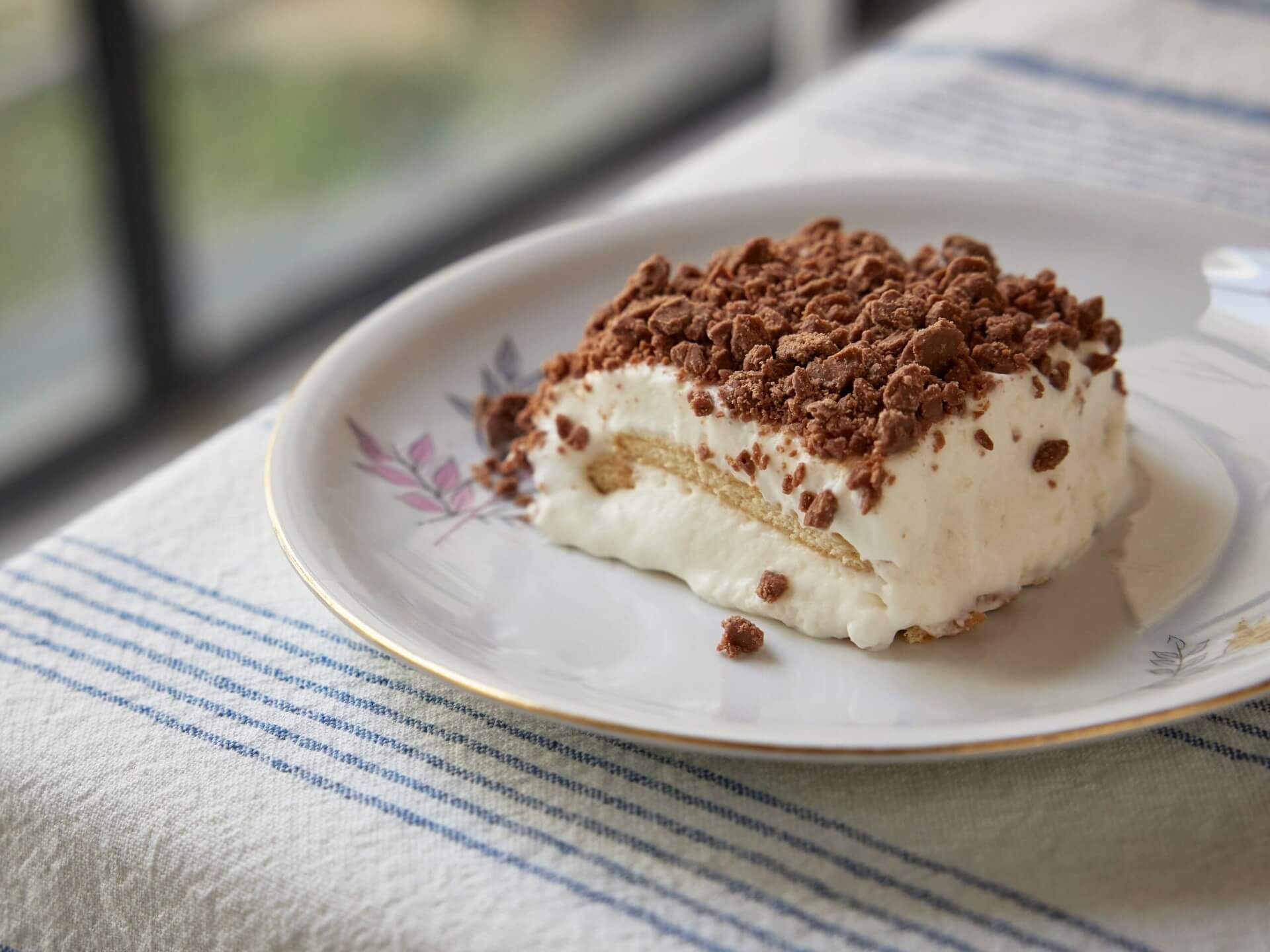 Slice of cake with cream on white plate with flowers
