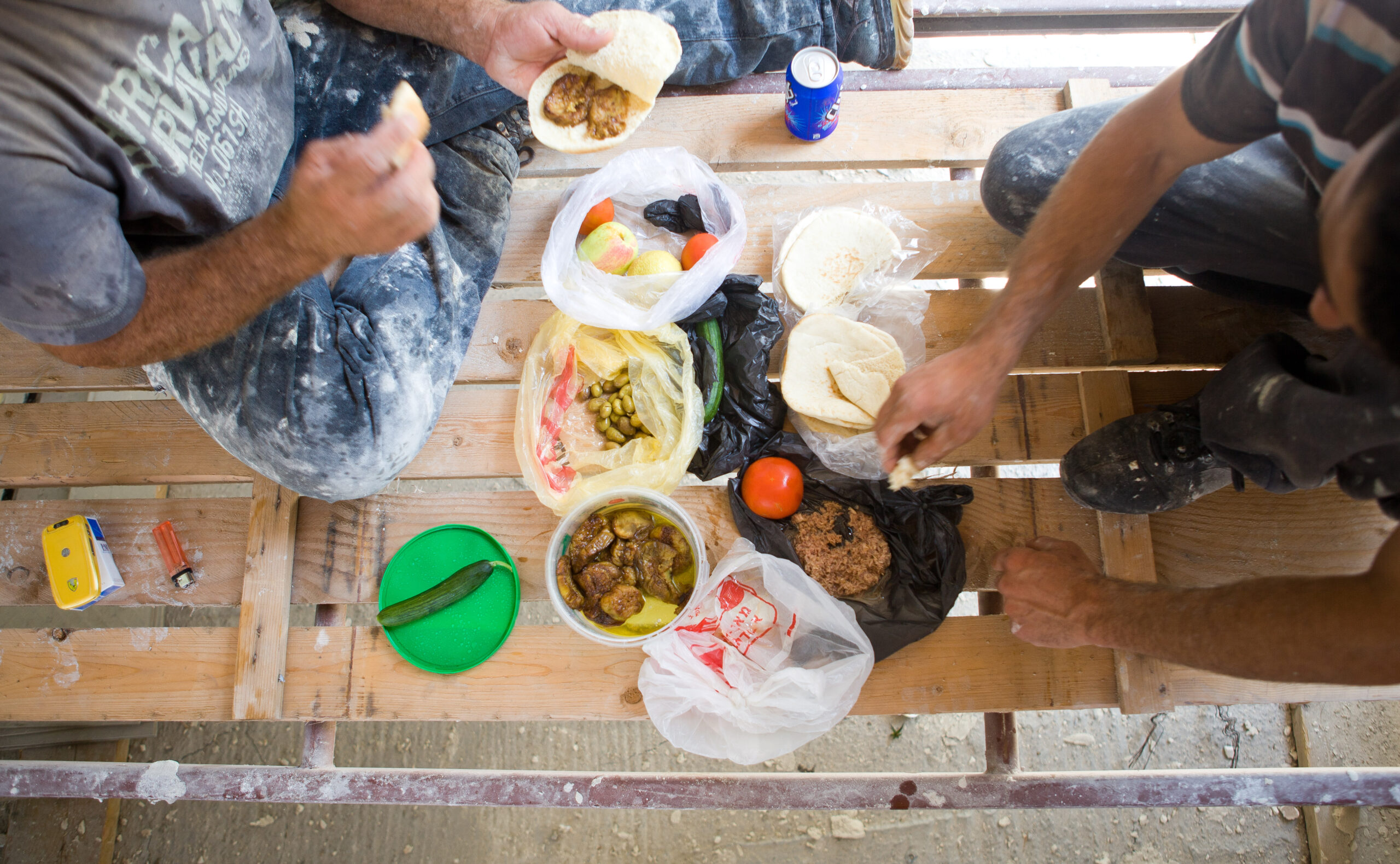 Construction workers eating a meal of olives, vegetables, and pita