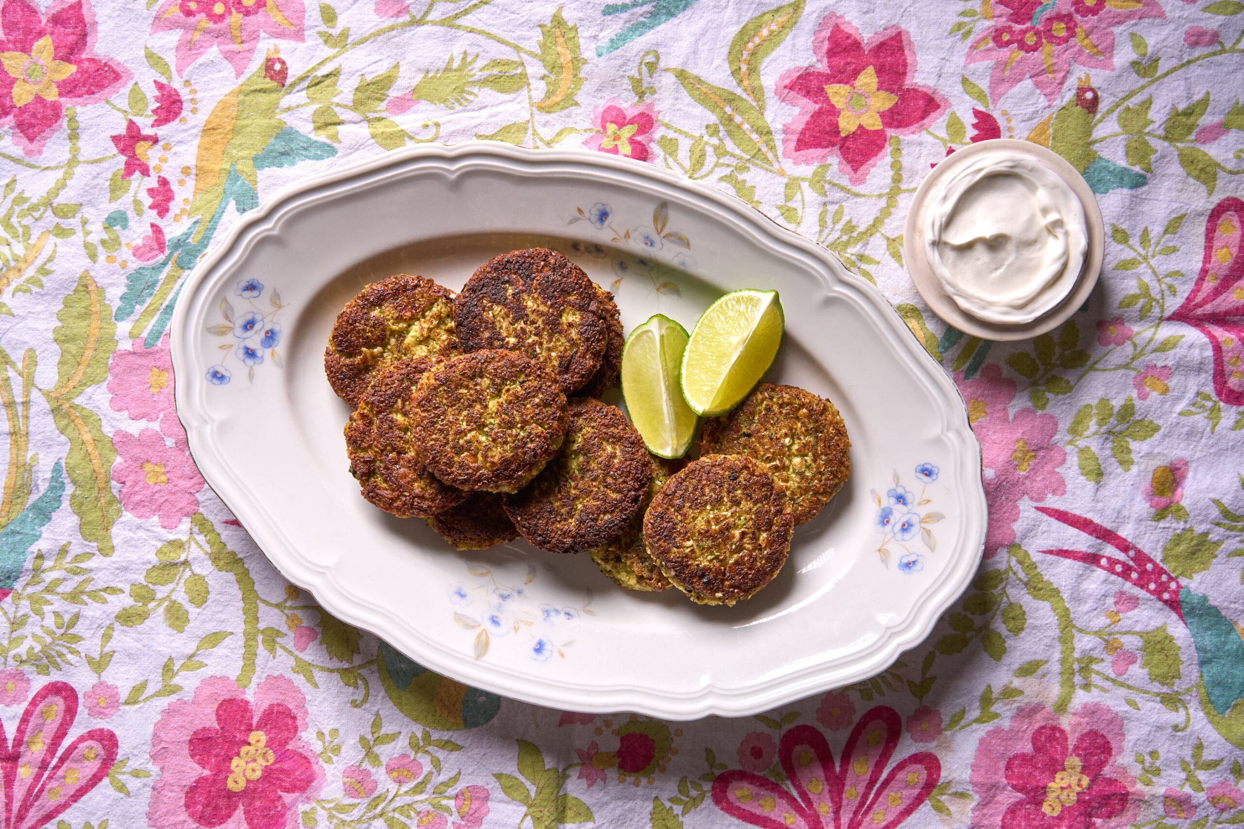Cauliflower fritters sit on a white oval-shaped platter with blue flower details