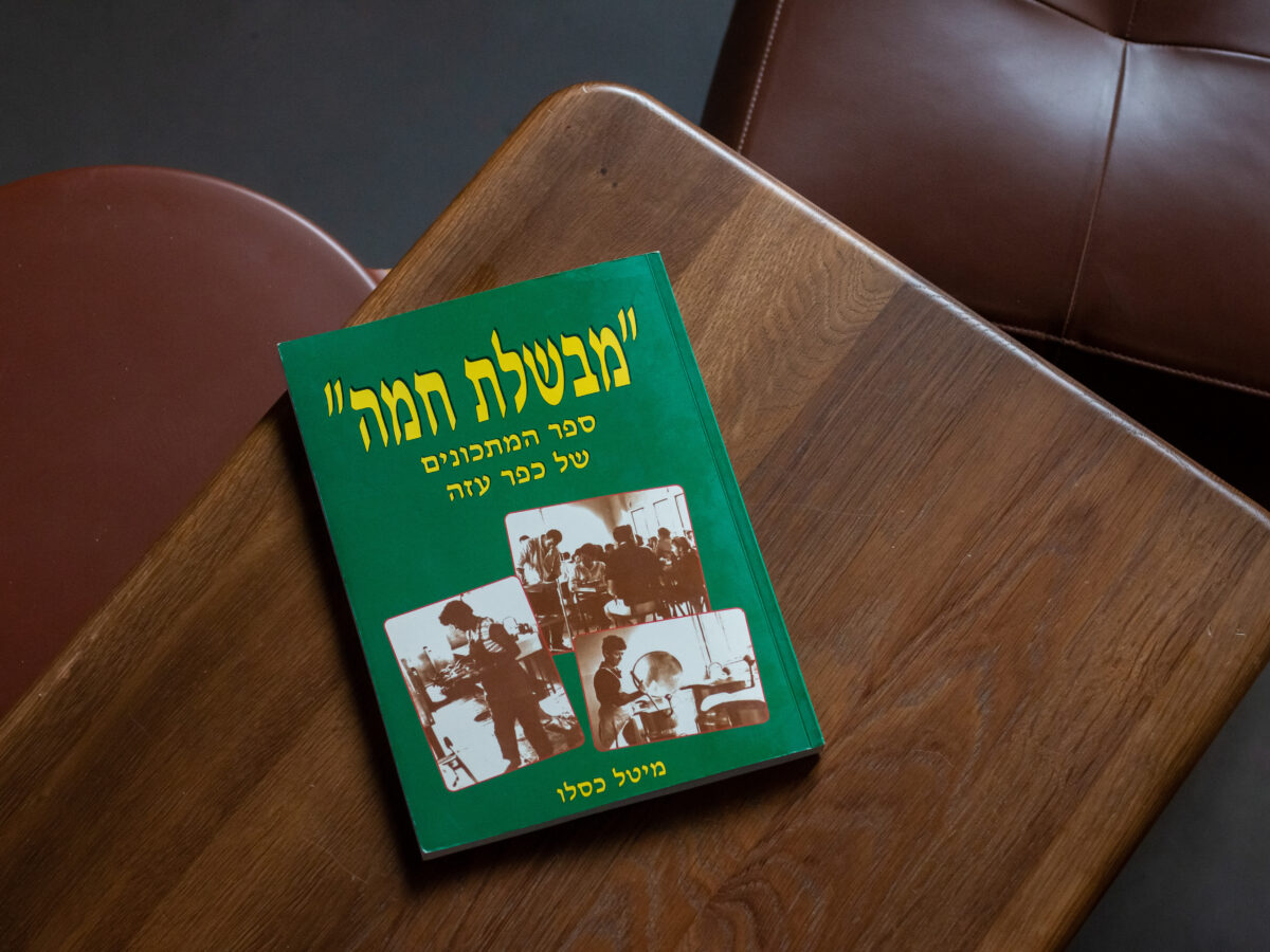 A community cookbook from Kibbutz Kfar Aza on a wooden table