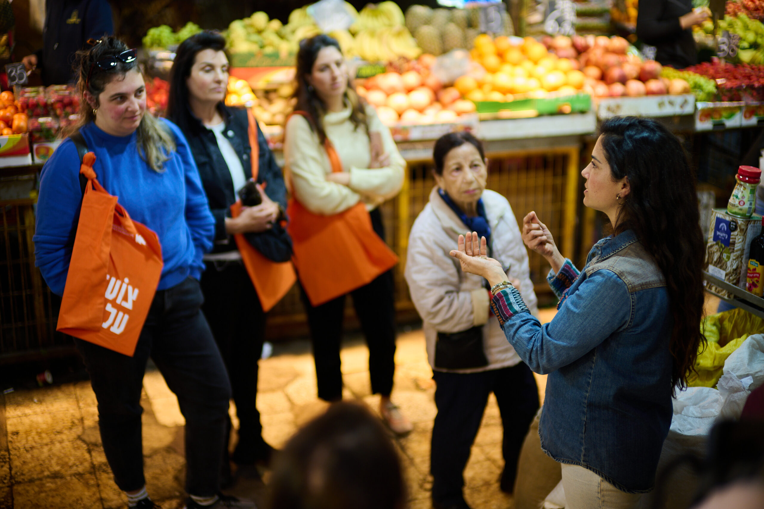 Woman leading a food tour in a market with attendees listening