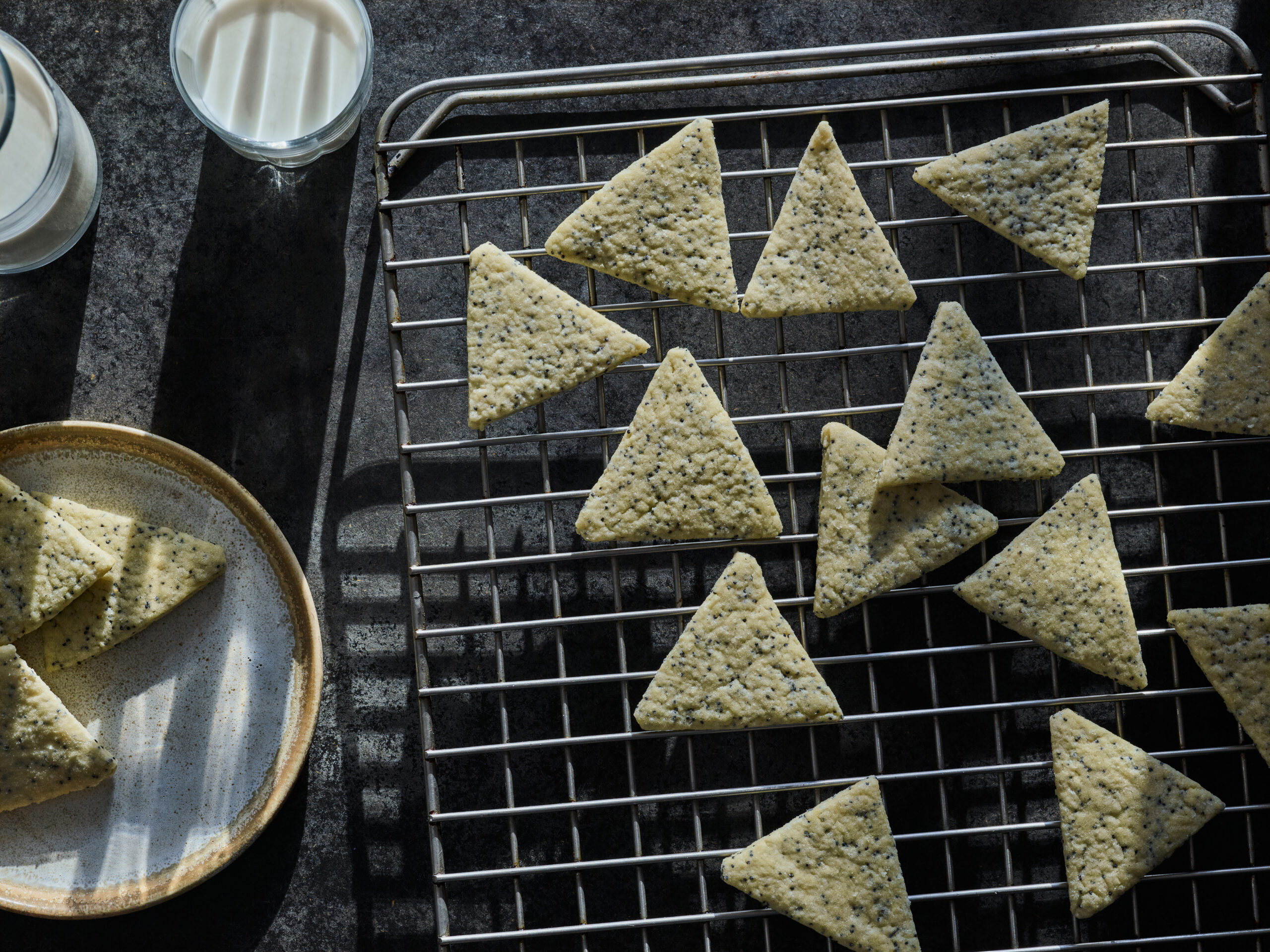 Triangular poppyseed cookies on a cooling rack